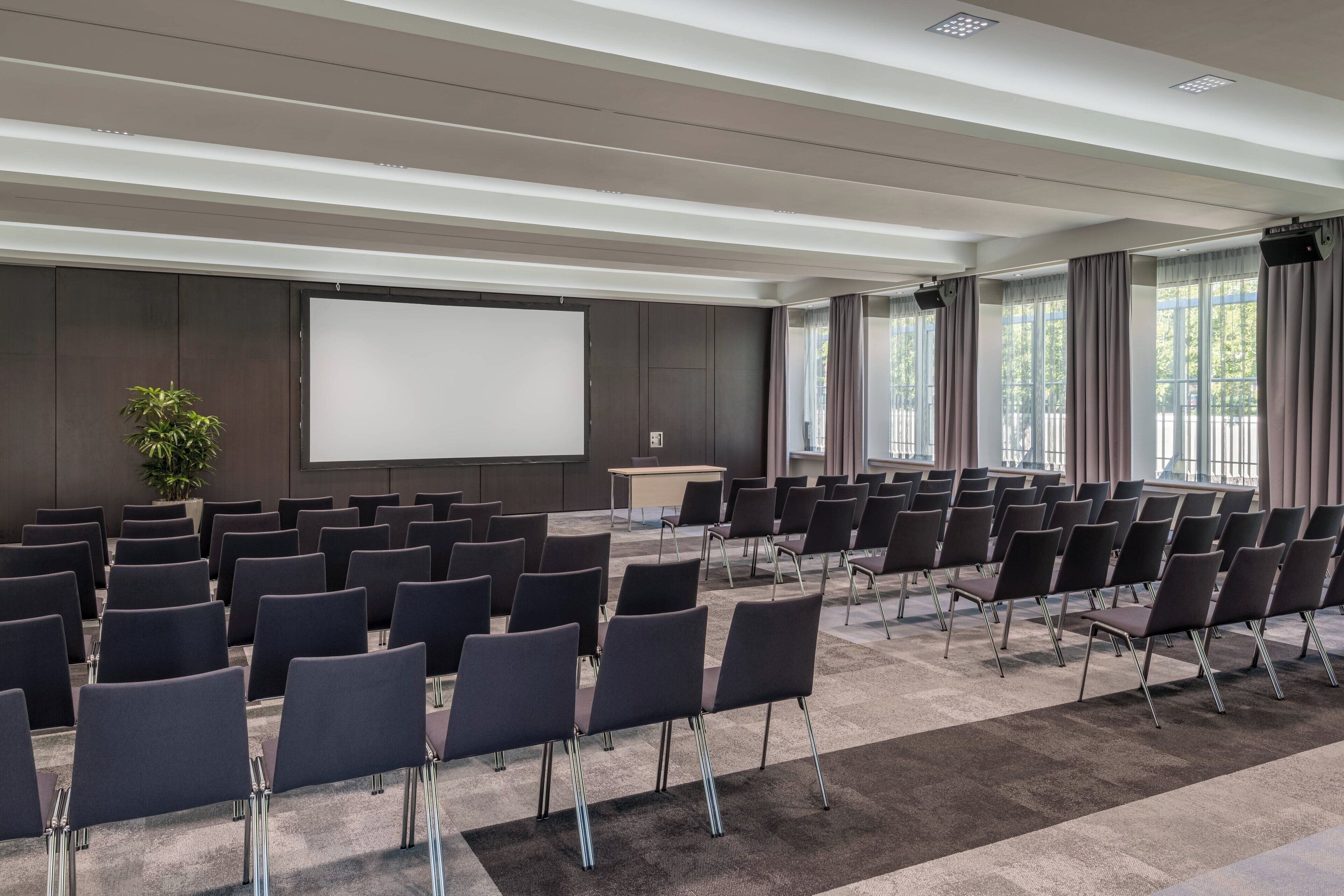 A conference room with rows of chairs, a large screen, and a podium.