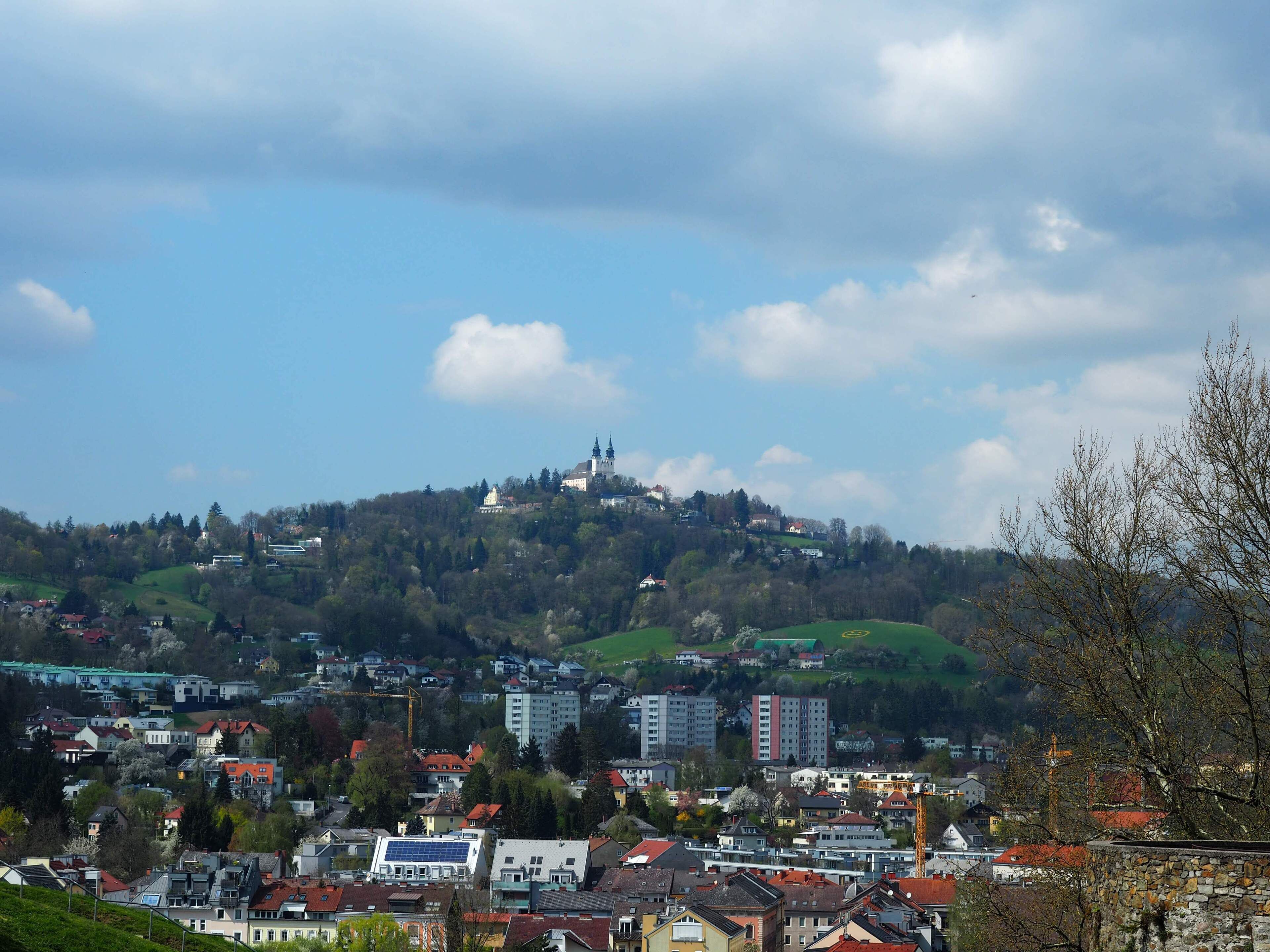 A town with a prominent hilltop church, residential buildings, and a mix of modern and traditional architecture.
