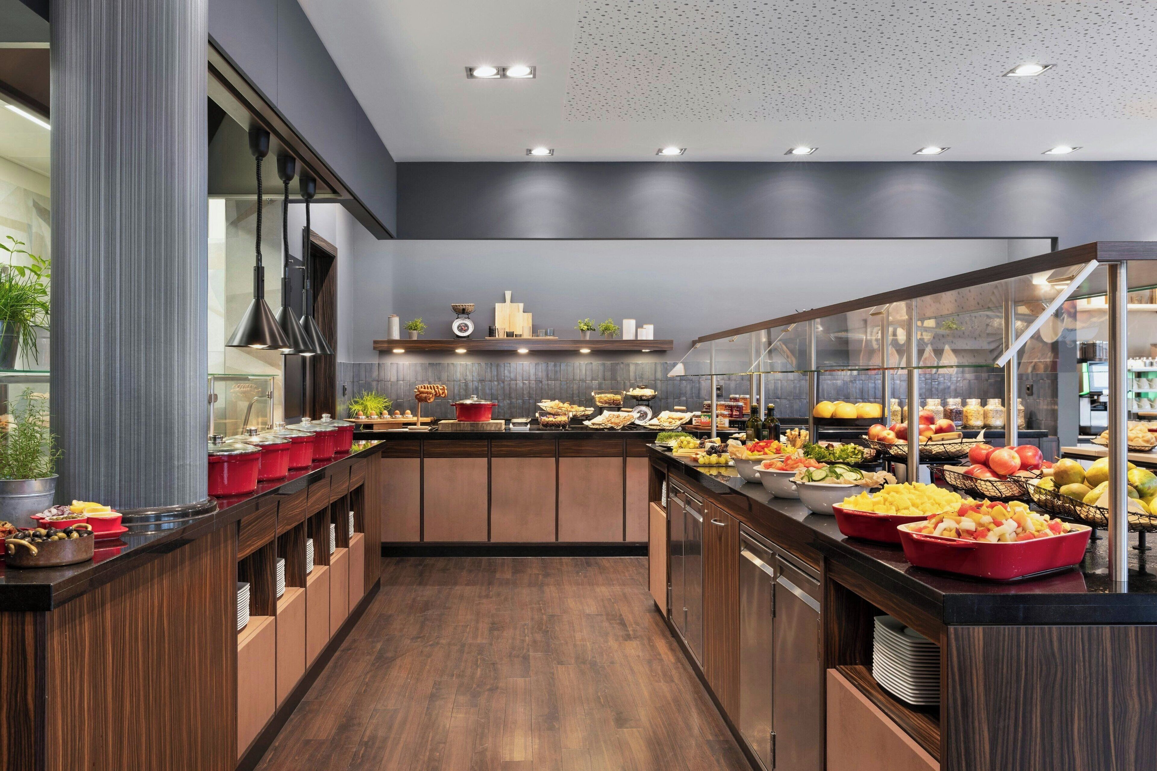 A modern kitchen with wooden cabinets, a central island with food, and a glass display case.