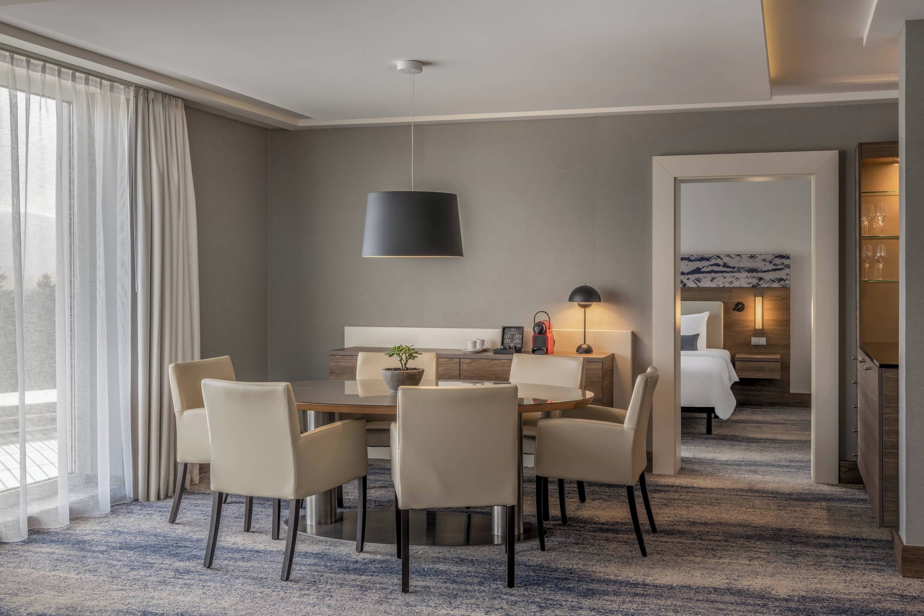 A hotel room with a dining area, a bed, and a bathroom.