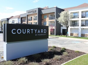 A sign for a Courtyard by Marriott hotel with a modern building in the background. - Courtyard by Marriott Layton (Layton)