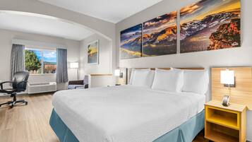 Una camera d'albergo con un letto grande, una scrivania, una sedia e una finestra con tende.