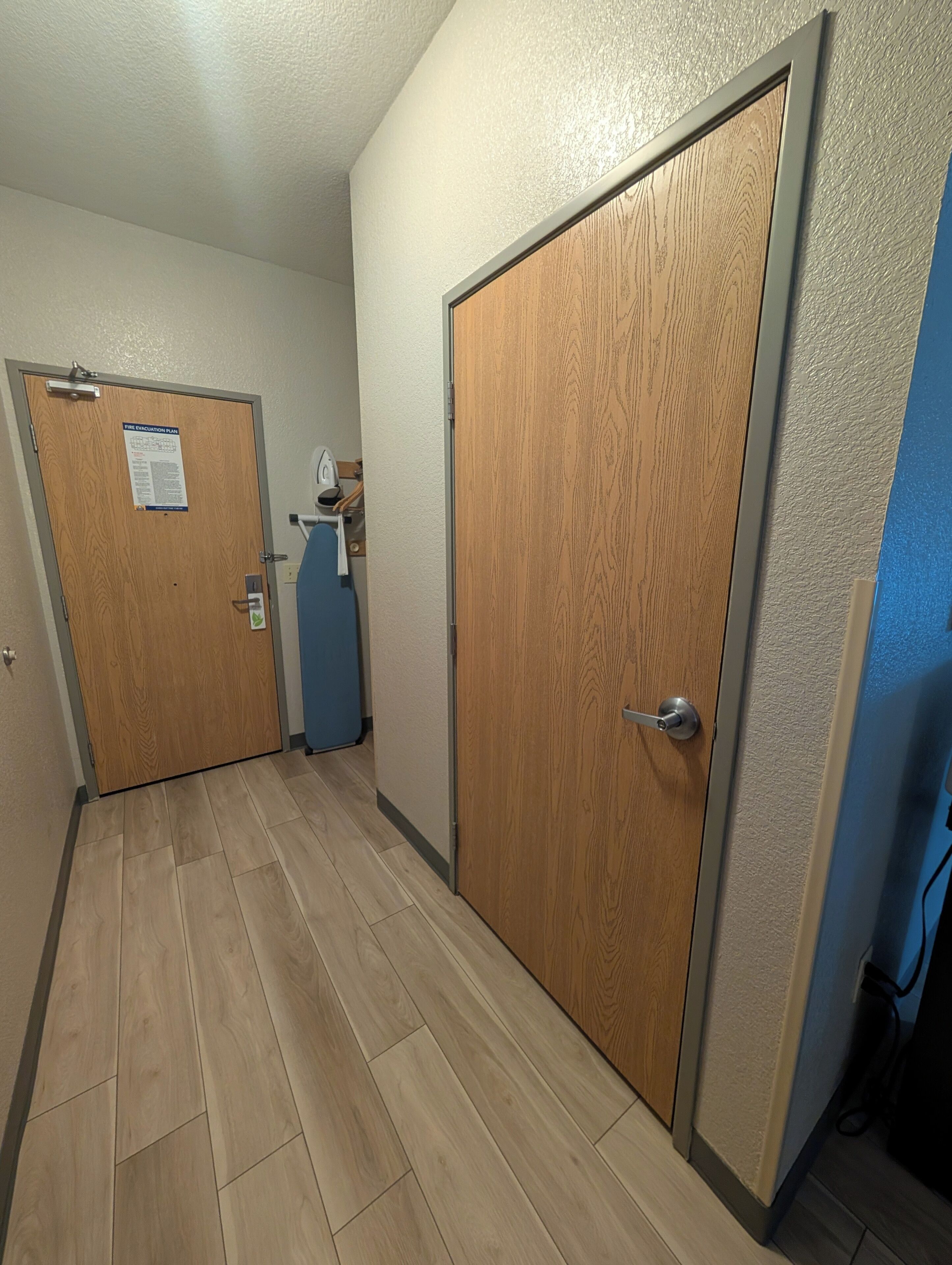 Un pasillo con puertas de madera, pared azul y techo blanco.