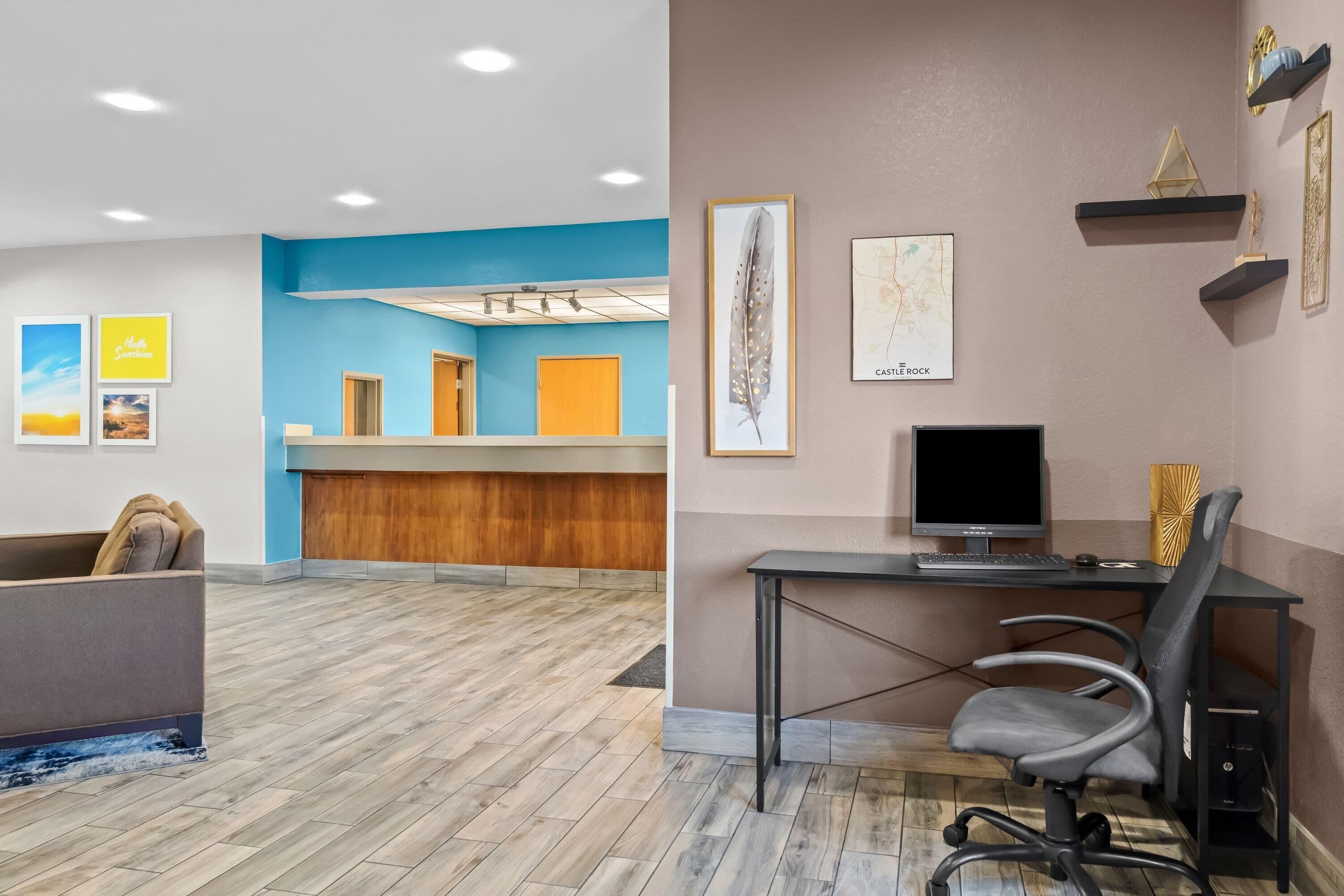 A reception area with a blue accent wall, wooden reception desk, and a grey sofa.