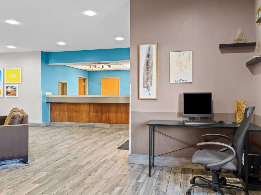 Un espace d’accueil avec un mur d’accent bleu, un comptoir d’accueil en bois et un canapé gris.