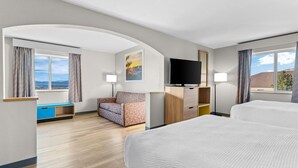 A hotel room with a large bed, a sofa, a desk, a TV, and a window with a view. - Days Inn & Suites by Wyndham Castle Rock (Castle Rock)