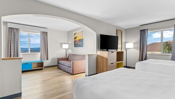 Une chambre d’hôtel avec un grand lit, un canapé, un bureau, une télévision et une fenêtre donnant sur un beau paysage.