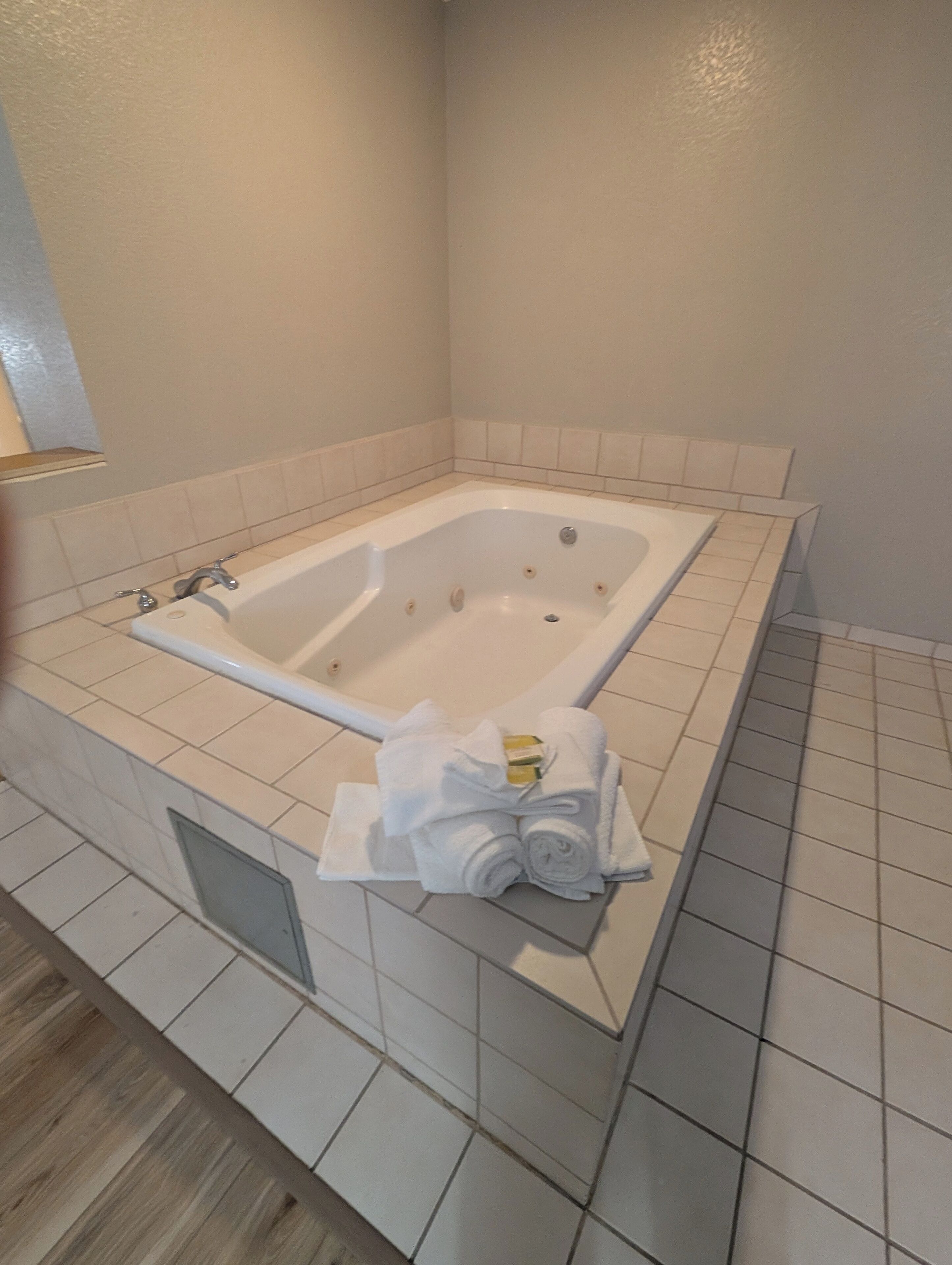 Une salle de bain avec une grande baignoire, des carreaux blancs et un porte-serviettes avec des serviettes.