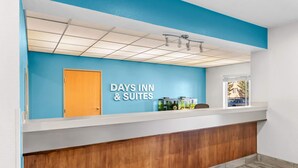 Un espace d’accueil avec un mur bleu, un comptoir de réception en bois et une enseigne indiquant « Days Inn & Suites ».