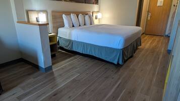 Een hotelkamer met een groot bed, houten vloeren en een schilderij aan de muur.