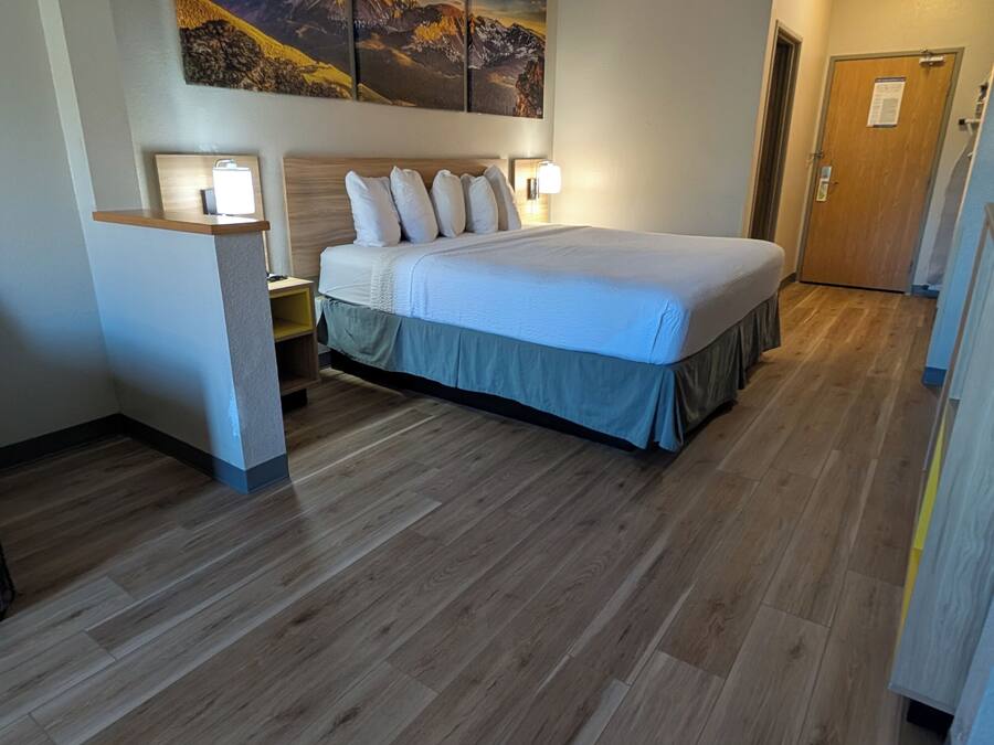 Een hotelkamer met een groot bed, houten vloeren en een schilderij aan de muur.