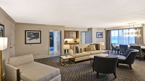 Una habitación de hotel con sofá, sillones, una mesa de comedor y zona de cocina.