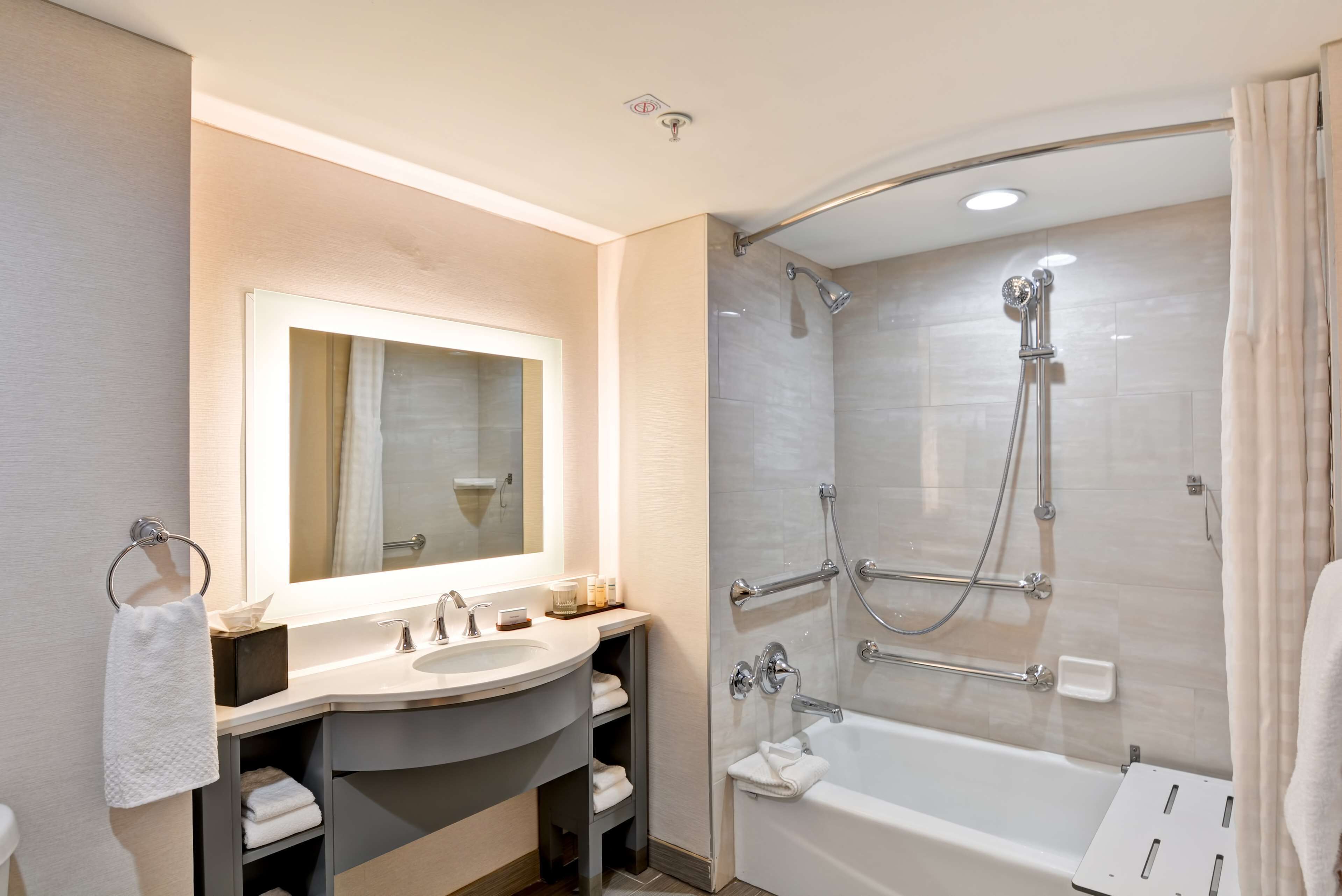 A modern bathroom with a vanity, sink, mirror, and a walk-in shower with a glass door.