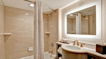A modern bathroom with a bathtub, shower, and a large mirror above the sink.