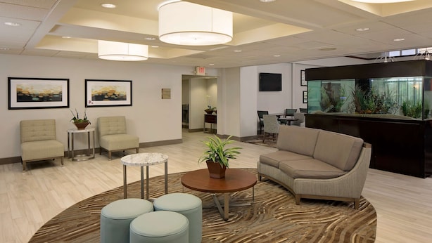 A modern lobby with seating, a reception desk, and a large aquarium. - Homewood Suites by Hilton Orlando-Maitland (Maitland)