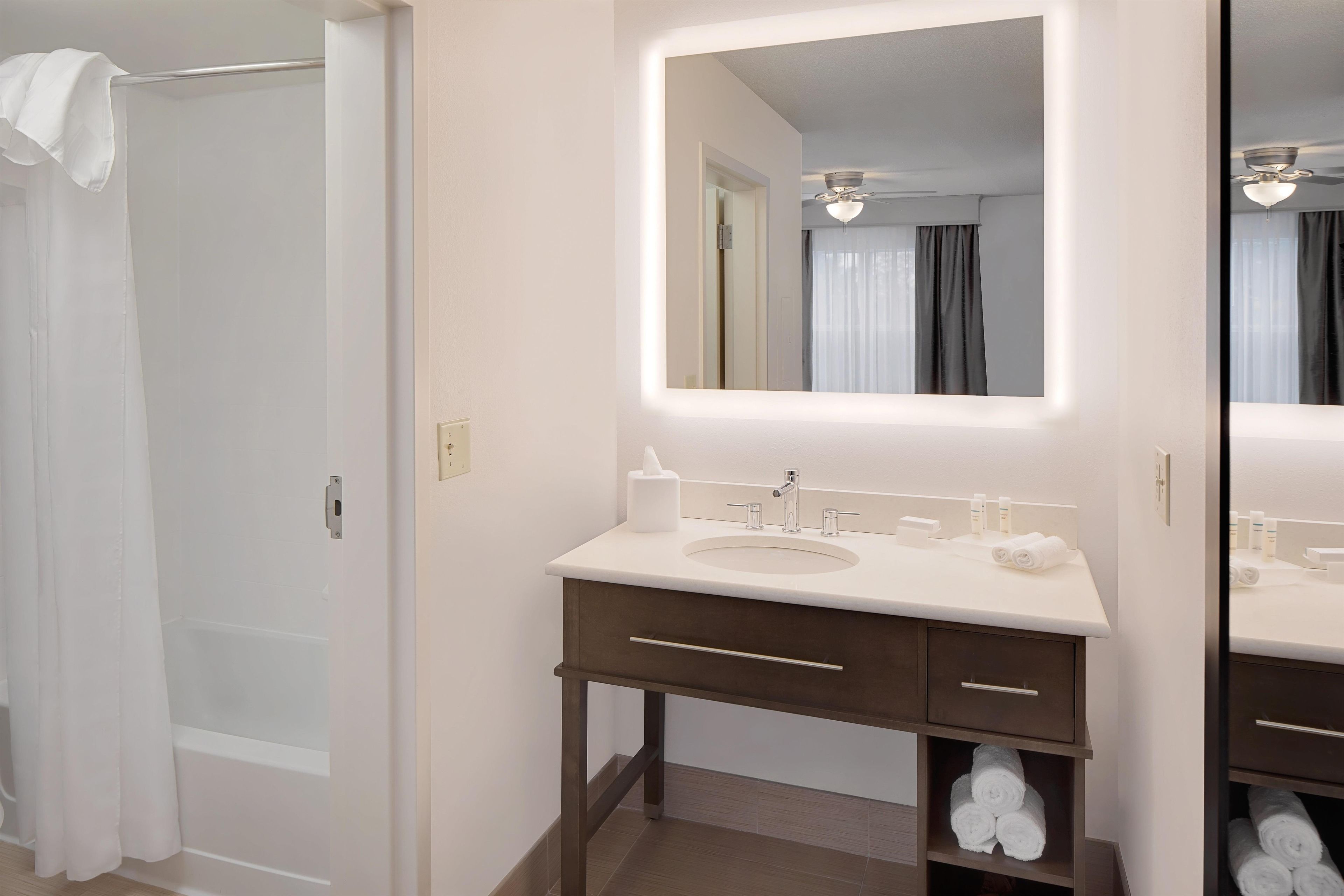 A bathroom with a white sink, a mirror, and a towel rack.