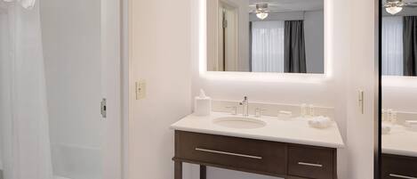 A bathroom with a white sink, a mirror, and a towel rack.