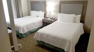 A hotel room with two beds, a nightstand, a lamp, and a patterned carpet.