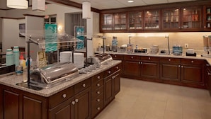 A hotel kitchen with a buffet setup, including a self-service station with a toaster, a coffee maker, and a waffle maker. - Homewood Suites by Hilton Orlando-Maitland (Maitland)