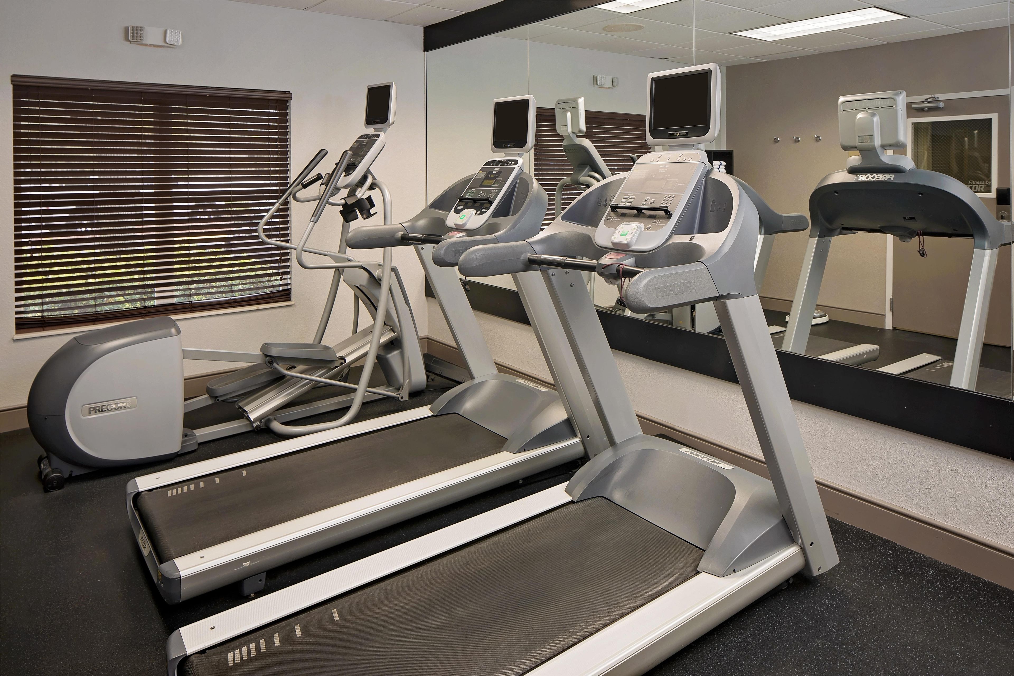 Un gimnasio con cintas de correr, elípticas y equipo de ejercicio.