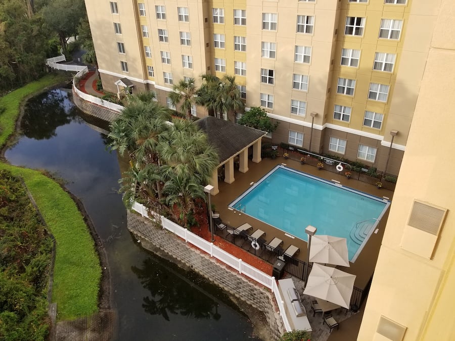 A hotel with a swimming pool, a white fence, and a water feature.