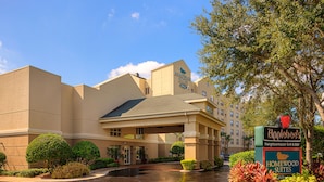 A hotel entrance with a covered walkway, a sign for Applebees, and well-maintained landscaping. - Homewood Suites by Hilton Orlando-Maitland (Maitland)