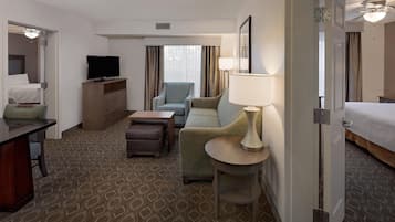 Habitación de hotel con cama, sofá, escritorio, televisor y lámpara.