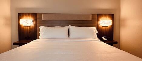Una habitación de hotel con una cama grande, dos mesitas de noche y lámparas de pared.