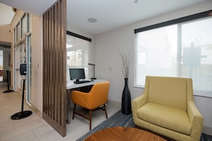 Un espacio de oficina moderno con un escritorio, una computadora y un sillón amarillo.