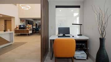 A modern office space with a desk, computer, and a vase with branches.