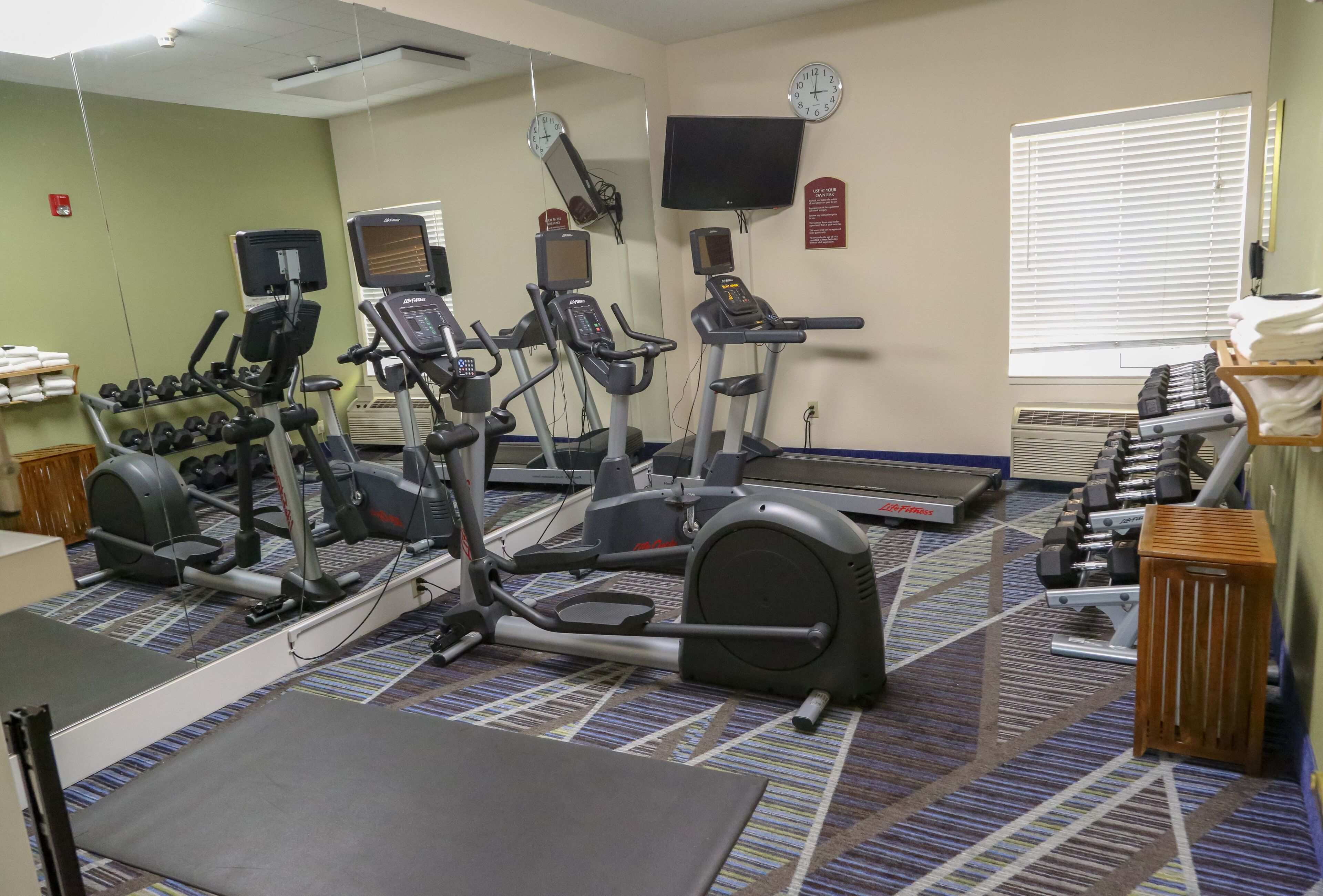 Ein Fitnessstudio mit Laufbändern, Crosstrainern und Kurzhanteln.