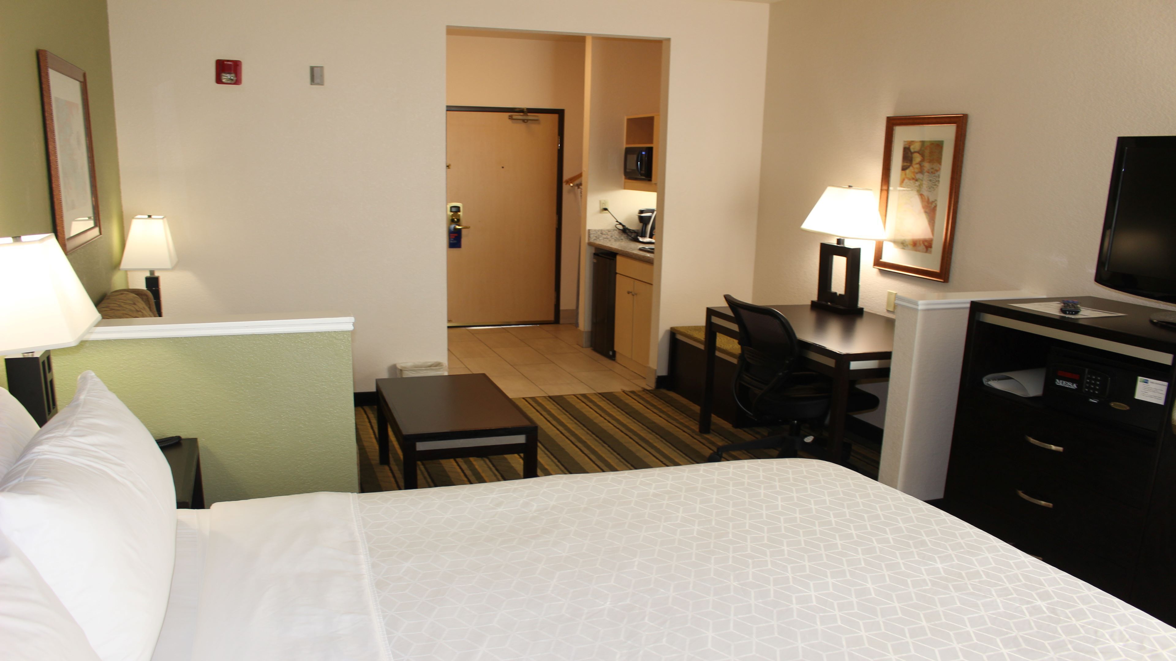 Une chambre d’hôtel équipée d’un lit, d’un bureau, d’une chaise et d’un coin cuisine.