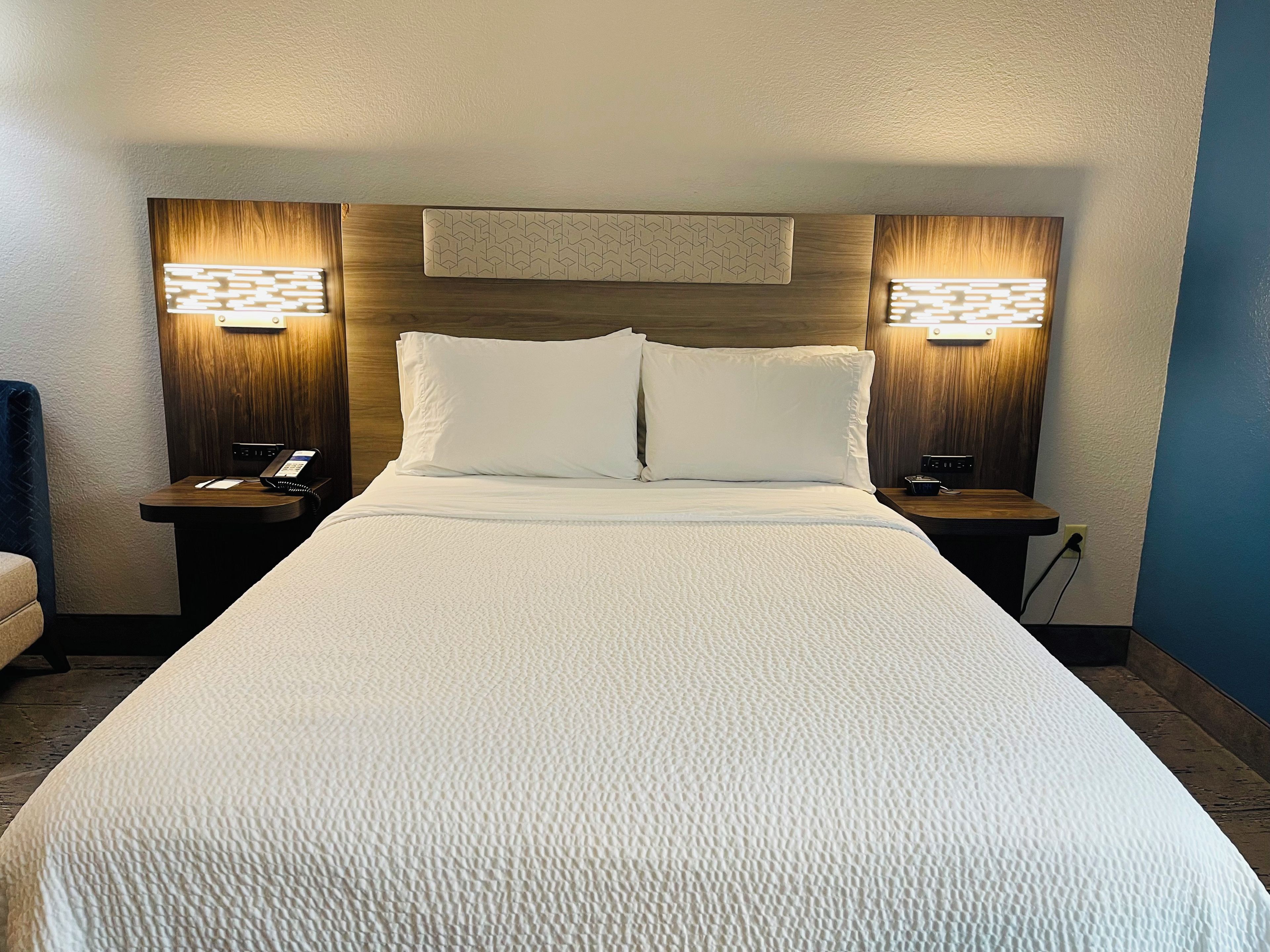 A hotel room with a large bed, two bedside tables with lamps, and a wooden headboard.