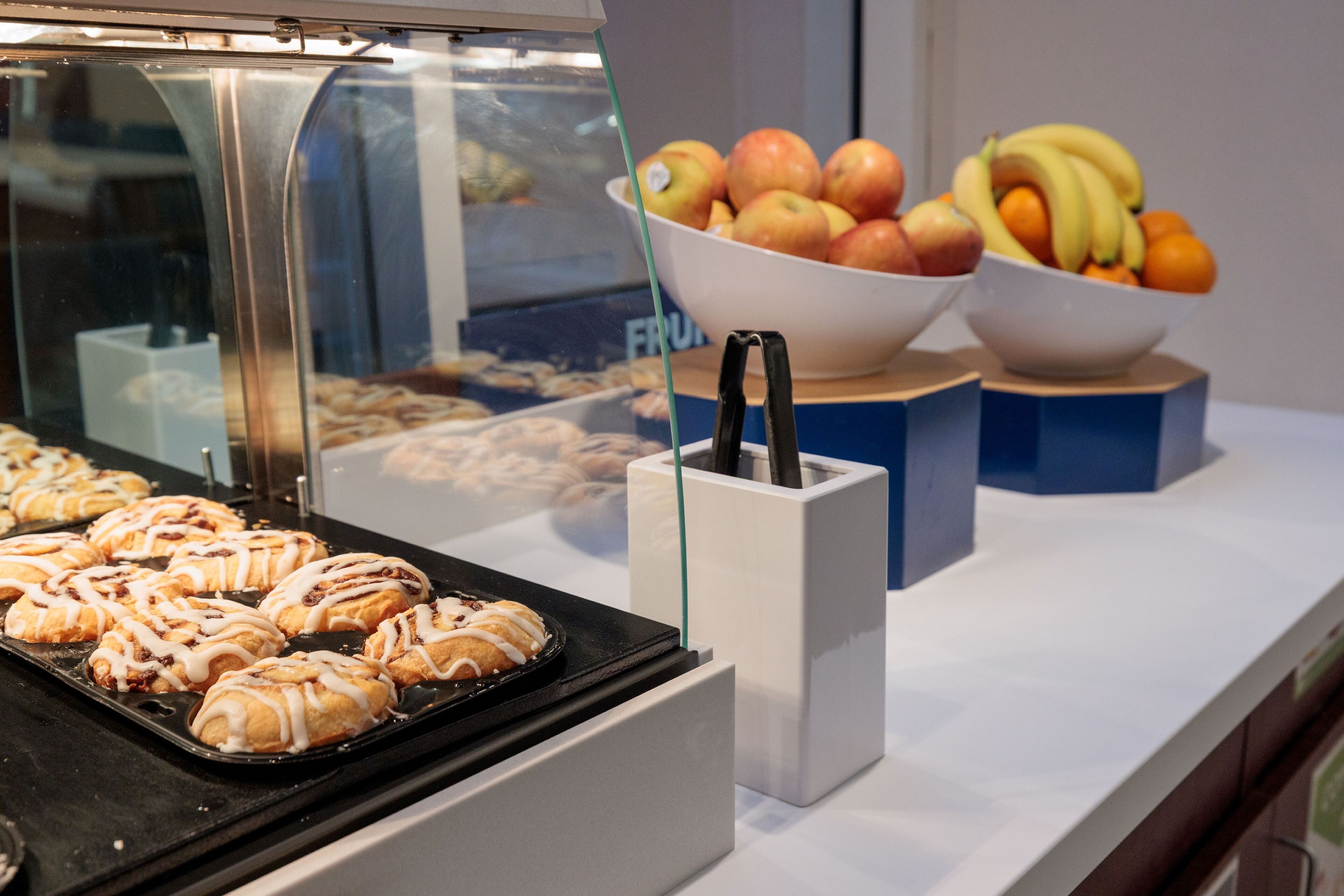 Una vitrina de panadería con pasteles y cuencos de fruta.