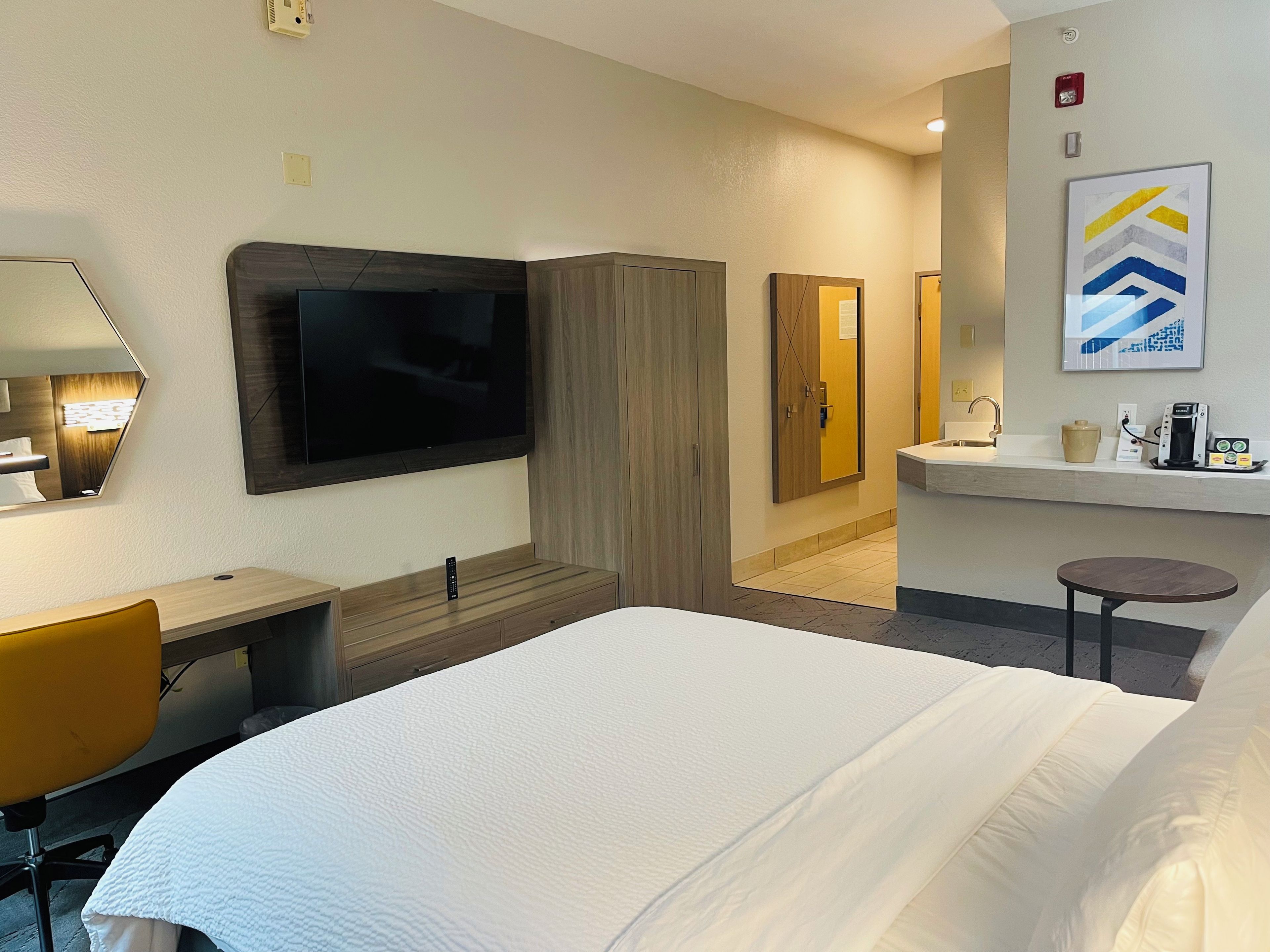 Une chambre d’hôtel comprenant un lit, un bureau, une télévision, une armoire, une salle de bain et une petite table.