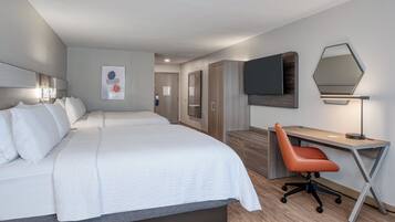 Ein Hotelzimmer mit einem großen Bett, einem Schreibtisch, einem Sessel, einem Fernseher und einem Kleiderschrank.