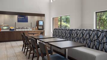 A modern dining area with a buffet, seating, and a view of trees.