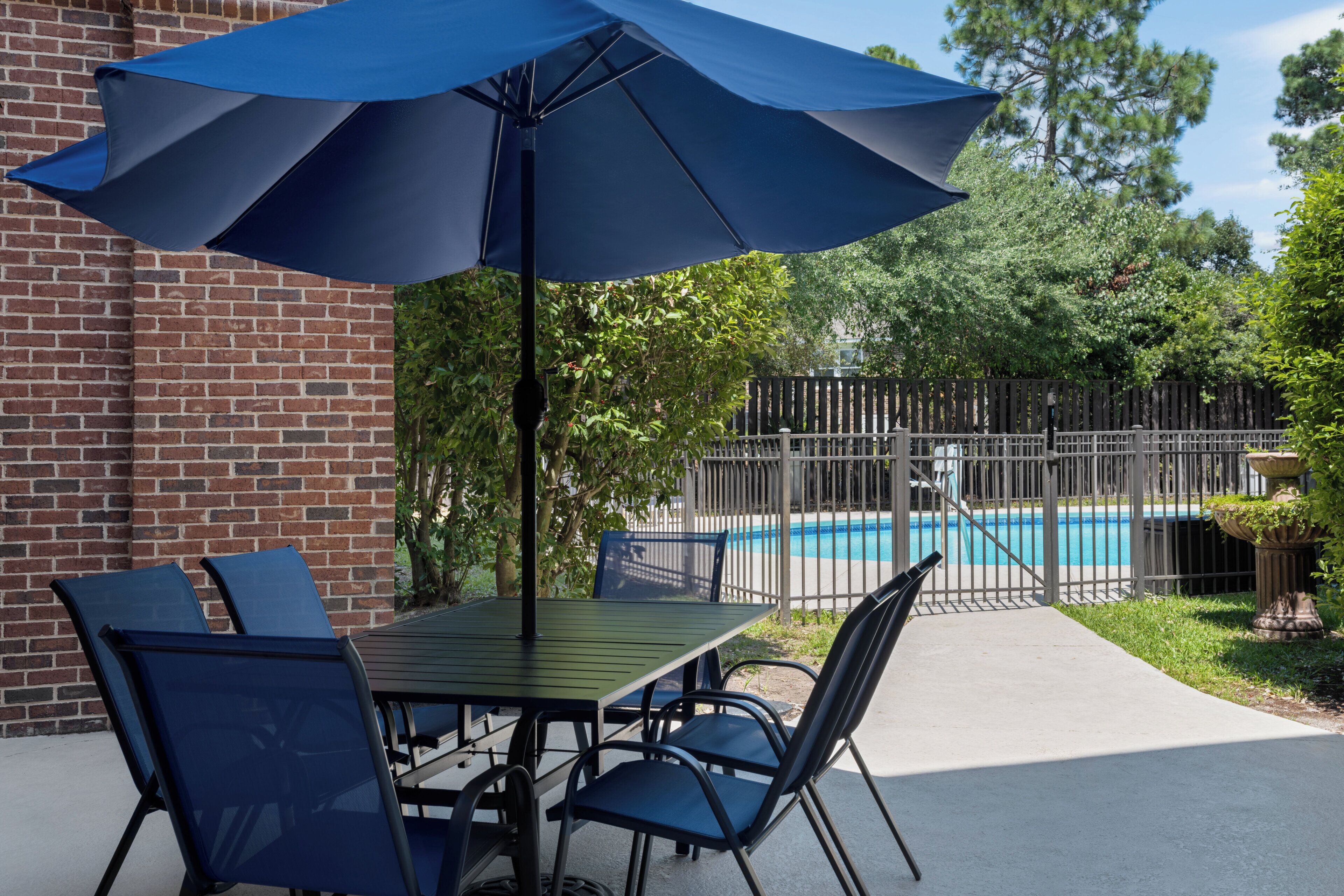 A patio with a table and chairs, a pool, and a fence.