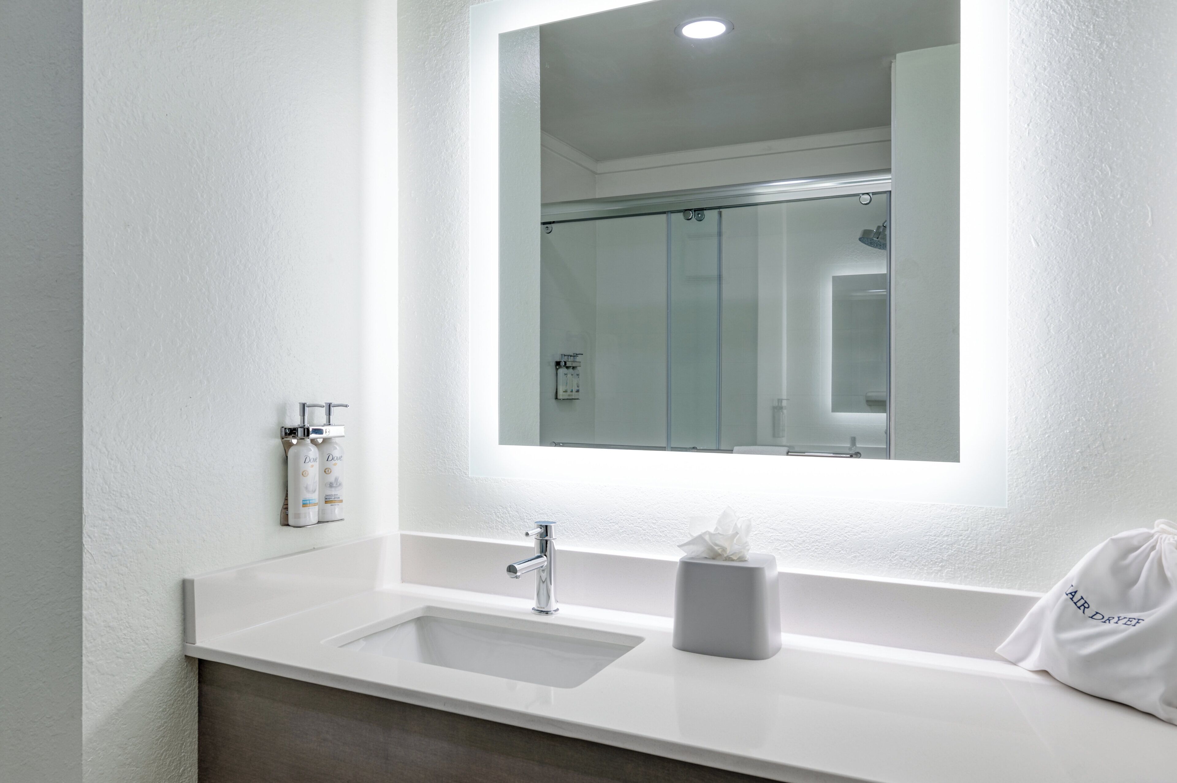 Une salle de bain avec un grand miroir, un lavabo et une douche.