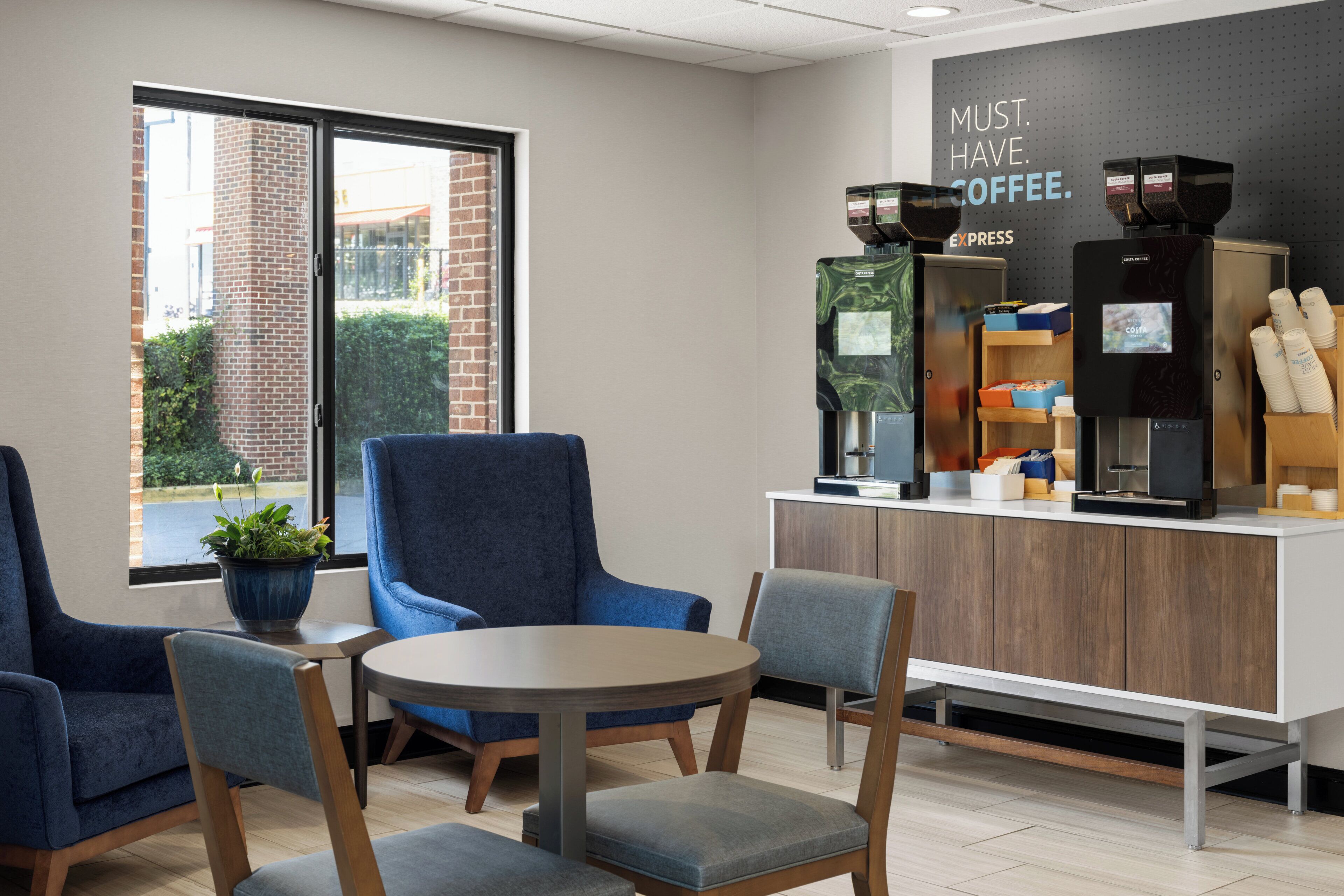 A coffee shop interior with seating, a coffee machine, and a sign that reads "MUST HAVE COFFEE."
