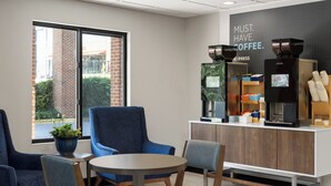 A coffee shop interior with seating, a coffee machine, and a sign that reads "MUST HAVE COFFEE." - Holiday Inn Express & Suites Columbia-I-20 @ Clemson Rd by IHG (Columbia)