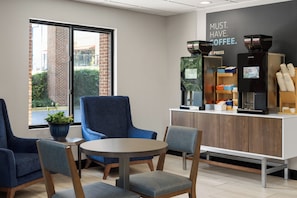A coffee shop interior with seating, a coffee machine, and a sign that reads "MUST HAVE COFFEE." - Holiday Inn Express & Suites Columbia-I-20 @ Clemson Rd by IHG (Columbia)