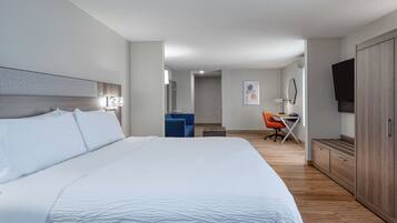 A hotel room with a large bed, a desk, a chair, and a TV.