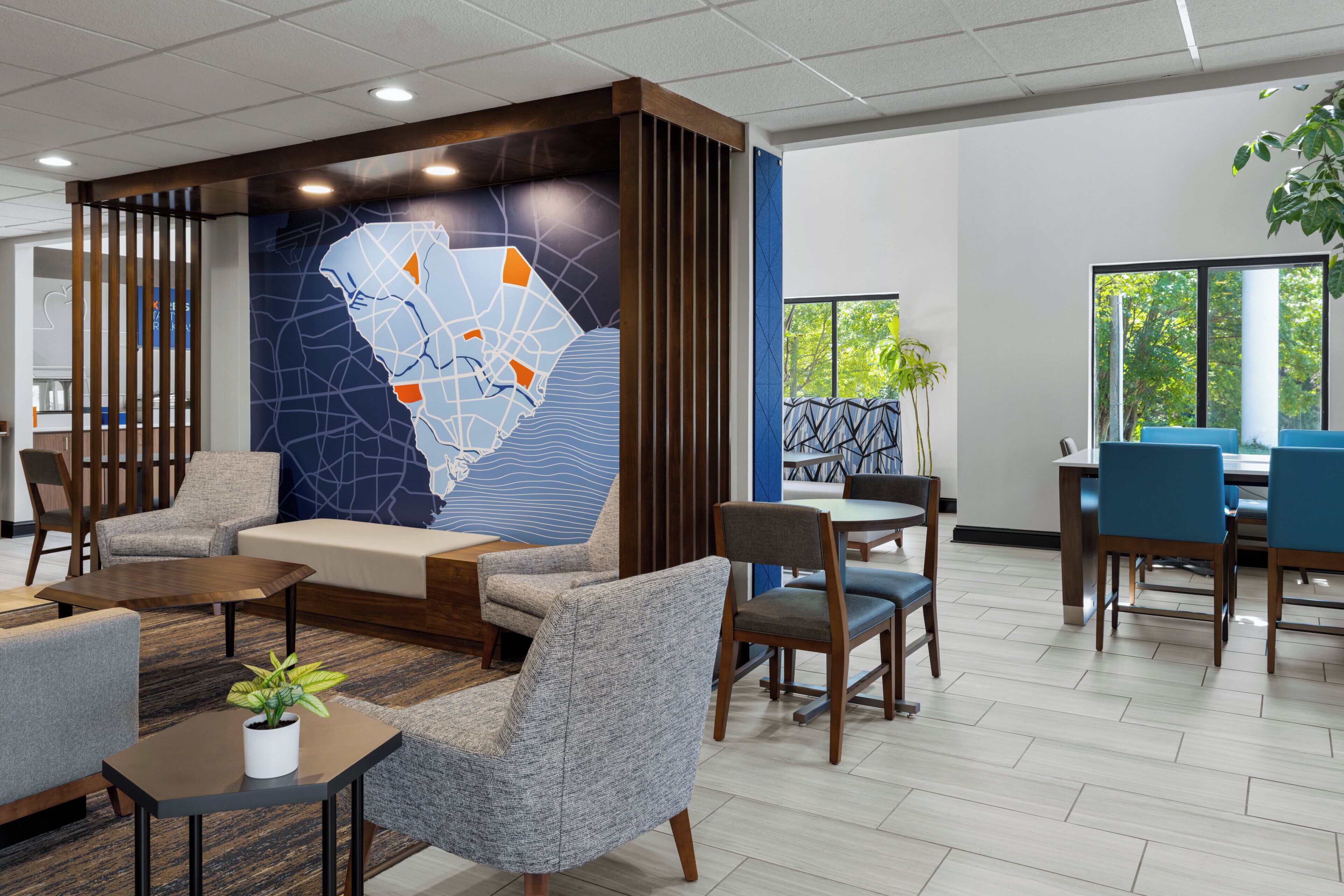 Um lobby moderno com áreas de estar, um mural de mapa e vista para o exterior.
