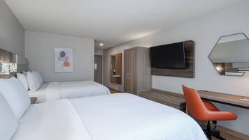 A hotel room with two beds, a desk, a chair, a TV, and a wardrobe.