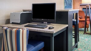 A hotel workspace with a desktop computer, keyboard, mouse, and a printer.