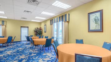 A conference room with round tables and chairs, a patterned carpet, and a framed picture on the wall.