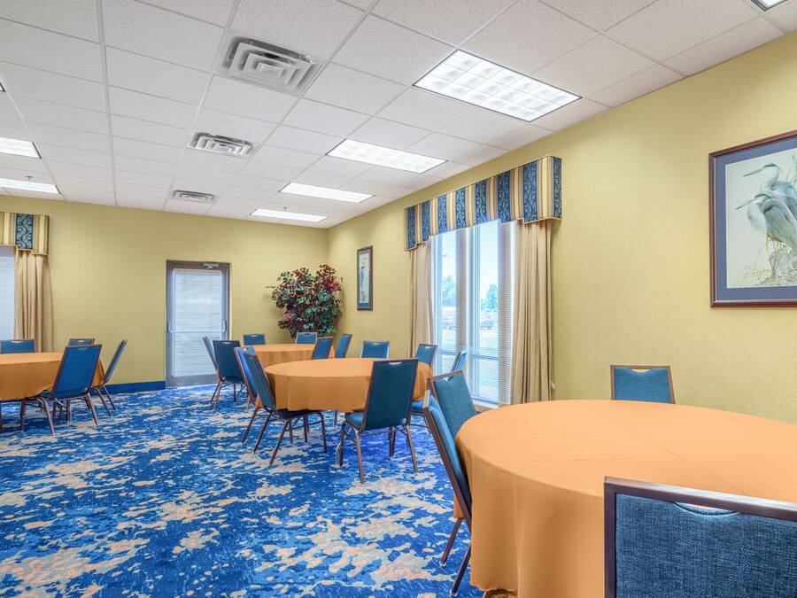 A conference room with round tables and chairs, a patterned carpet, and a framed picture on the wall.