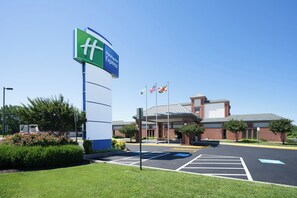 A Holiday Inn Express sign, a parking lot, and a building with a covered entrance. - Holiday Inn Express Cambridge by IHG (Cambridge)