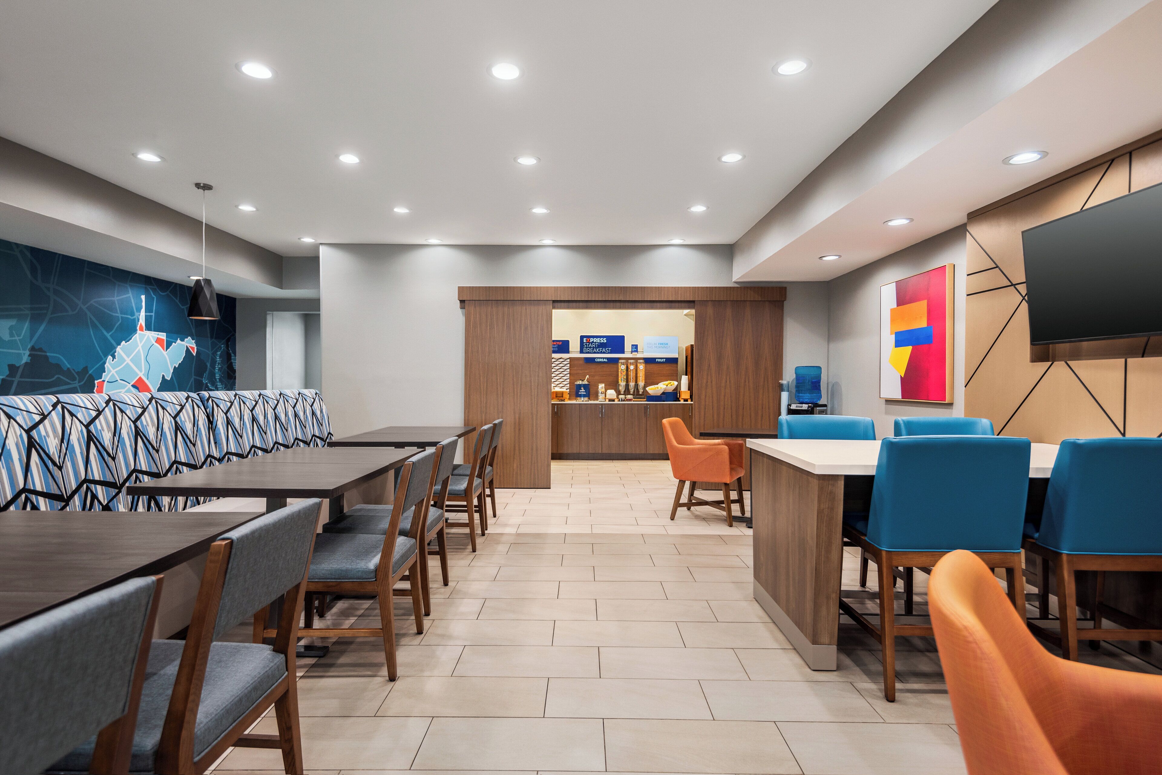 Un espace de restauration moderne dans un hôtel, comprenant une longue table conviviale, des tables individuelles et un bar.